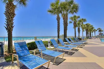 a row of blue beach chairs next to the beach at Sterling Reef 1704 in Panama City Beach