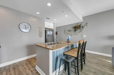 a kitchen with a sink and a counter with chairs at Sterling Reef 1704 in Panama City Beach
