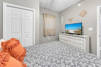 a bedroom with a bed and a dresser with a tv at Sterling Reef 1704 in Panama City Beach