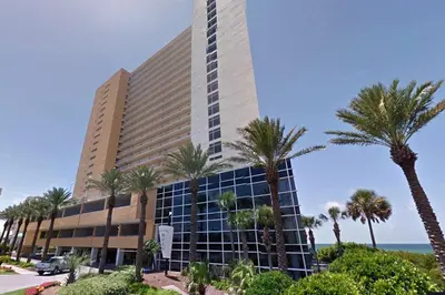 a large building with palm trees in front of the ocean at Sterling Reef 1704 in Panama City Beach