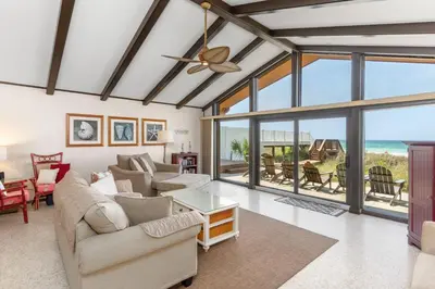 a living room with a ceiling fan and large windows at GULF FRONT 3BD/2BA Home with private beach access! in Panama City Beach