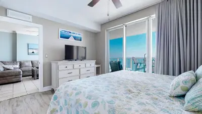 a bedroom with a bed and a television and a balcony at Huge Balcony - Beachfront - Renovated - FLPCB87 in Panama City Beach