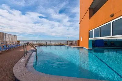 a large swimming pool next to a building with the ocean at Huge Balcony - Beachfront - Renovated - FLPCB87 in Panama City Beach