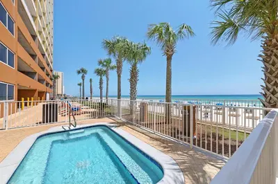 a swimming pool with palm trees and the beach at Huge Balcony - Beachfront - Renovated - FLPCB87 in Panama City Beach