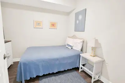 a white bedroom with a bed and a table at Seychelles 1609 in Panama City Beach