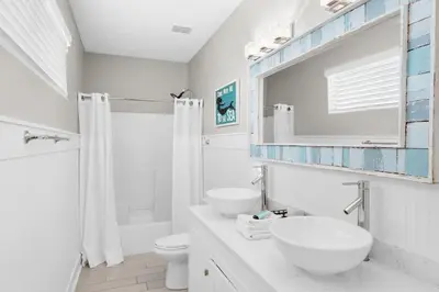 a white bathroom with two sinks and a shower at Golden Shores in Panama City Beach