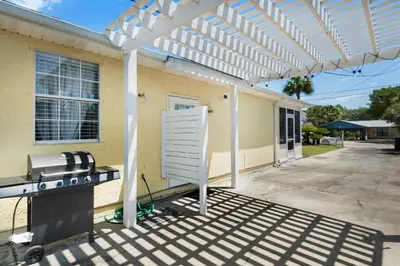 a barbecue under a white pergola outside of a house at Golden Shores in Panama City Beach