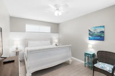 a white room with a bed and a chair at Golden Shores in Panama City Beach