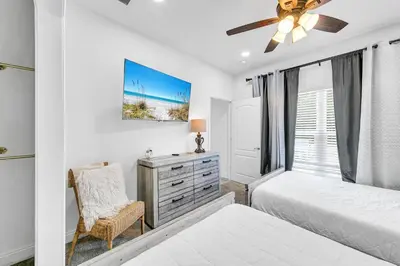 a bedroom with a bed and a dresser and a window at Rustic Oasis in Panama City Beach