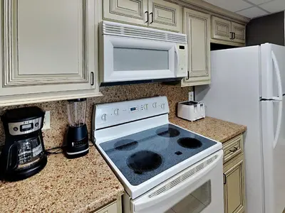 a kitchen with a white stove top oven next to a refrigerator at Edgewater Leeward #603 in Panama City Beach