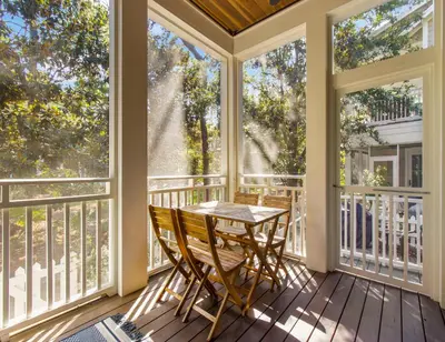 a screened porch with a table and chairs and windows at Anchored on 30A in Santa Rosa Beach
