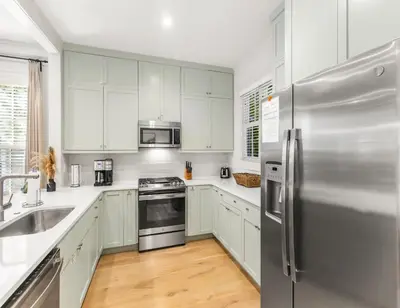 a kitchen with white cabinets and a stainless steel refrigerator at Anchored on 30A in Santa Rosa Beach