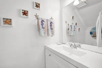 a white bathroom with a sink and a mirror at Sandcastles and Sunshine - Gulf Highlands Beach Resort in Panama City Beach