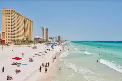 a group of people on a beach near the ocean at Sandcastles and Sunshine - Gulf Highlands Beach Resort in Panama City Beach