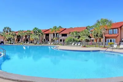 a large swimming pool at a resort with palm trees at Sandcastles and Sunshine - Gulf Highlands Beach Resort in Panama City Beach
