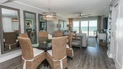 a dining room and living room with a dining table and chairs at 5-STAR BEACHFRONT D505 - Total Remodel - Nov & Dec Snowbirds Welcome! in Panama City Beach