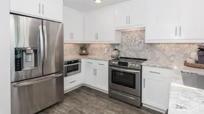 a kitchen with white cabinets and stainless steel appliances at 5-STAR BEACHFRONT D505 - Total Remodel - Nov & Dec Snowbirds Welcome! in Panama City Beach